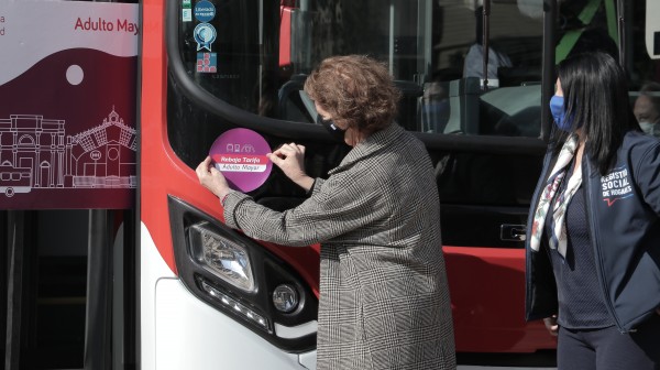 Ministra Hutt poniendo sticker en bus Red